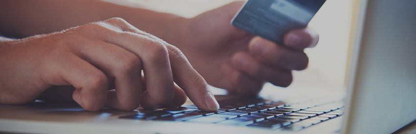 Hands typing credit card number on a laptop